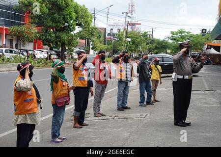 Makassar, Indonesia, 17 agosto 2021. Un poliziotto di Makassar celebra il 76° giorno dell'Indipendenza indonesiana in modo unico. Questo poliziotto ha invitato gli addetti al parcheggio a svolgere la cerimonia praticamente mentre si guarda un telefono cellulare che stava trasmettendo una trasmissione in diretta della cerimonia della bandiera al Palazzo di Stato. Credit: Herwin Bahar/Alamy Live News Foto Stock