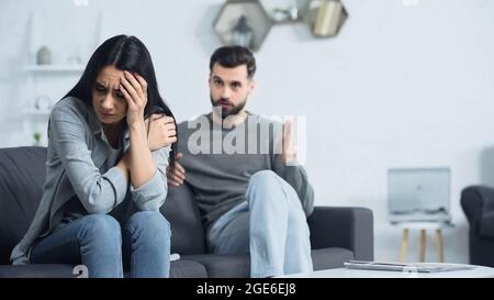 donna frustrata seduta vicino blured e dispiaciuto ragazzo Foto Stock