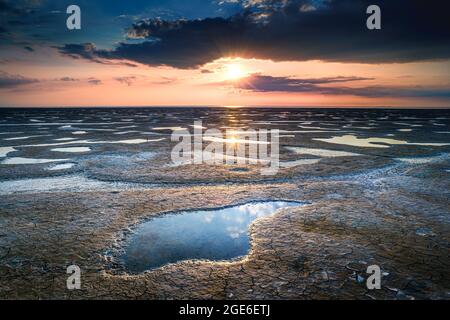 Bella estate. Costa del mare bagnata dalla pietra, l'alba si riflette sulla sabbia bagnata. Paesaggio del mattino. Foto Stock