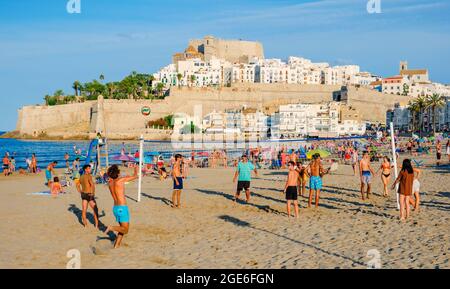 PENISCOLA, SPAGNA - 2 AGOSTO 2021: Persone che si godono sulla spiaggia di Peniscola, a Valencia, mettendo in risalto le sue mura fortificate sullo sfondo. È un Foto Stock