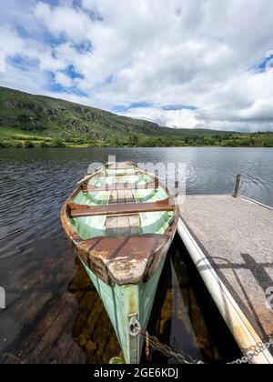 Incatenato su barca a remi a un molo su un lago in Irlanda Foto Stock