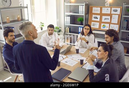 Il manager senior del business man dà istruzioni ai suoi subordinati in occasione di una riunione in un ufficio moderno. Foto Stock