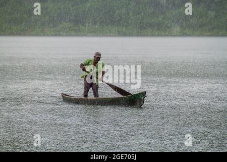 PORTOBELO, PANAMA - 28 MAGGIO 2016: Uomo locale nella sua canoa durante una pioggia pesante. Foto Stock