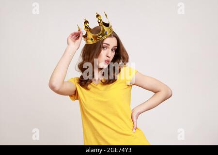 Ritratto di giovane soddisfatta bella principessa adolescente indossa in T-shirt gialla e corona diadema dorata, guardando la fotocamera con gesto KISS. Indo Foto Stock