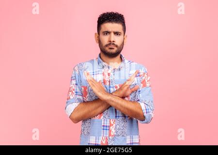 Mai, nessun compromesso! Ritratto di uomo insoddisfatto bearded in camicia blu che attraversa le mani, mostrando il segno x, il divieto o il gesto di divieto, rifiutando l'offerta. Foto Stock