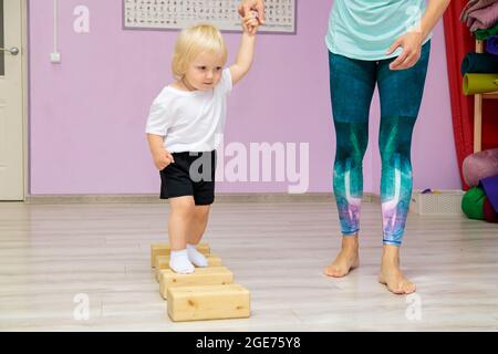 Mamma e bambino stanno facendo esercizi di sviluppo in palestra. Esercizi di sviluppo per il bambino. Foto Stock