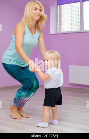 Mamma e bambino stanno facendo esercizi di sviluppo in palestra. Esercizi di sviluppo per il bambino. Foto Stock