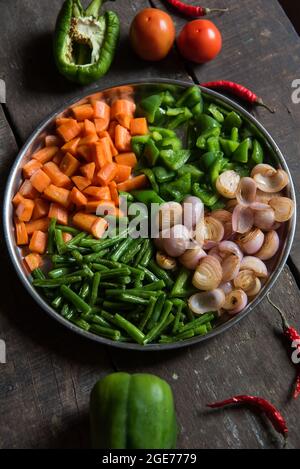 Carote, fagioli, cipolla e capsicum verde tritati al momento con uso di fuoco selettivo. Pronti per cucinare gli oggetti. Vista dall'alto Foto Stock