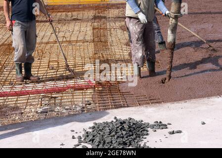 I costruttori lavorano sul cantiere: Versando calcestruzzo marrone per fondazione Foto Stock