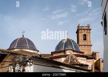 La cima del tetto della chiesa principale 'San Roque' con cupole piastrellate blu e torre del 18 ° secolo a Oliva, Spagna Foto Stock