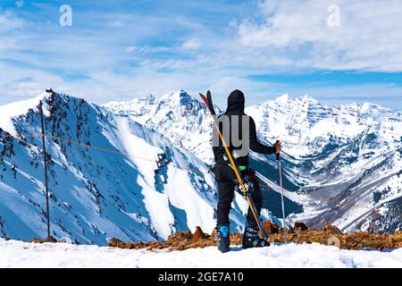 Uomo con sci e polo di sci al Summit of Massive Winter Mountain Landscape Foto Stock