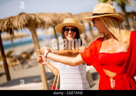 Due graziose giovani donne che camminano su una spiaggia in estate Foto Stock