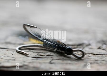 Pesca di salmone lucido volare con flash giallo su una superficie di legno Foto Stock