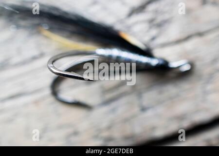 Pesca di salmone lucido volare con flash giallo su una superficie di legno Foto Stock