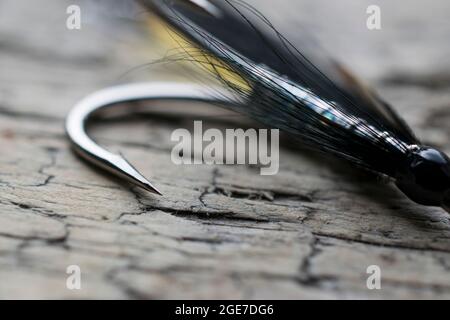 Pesca di salmone lucido volare con flash giallo su una superficie di legno Foto Stock