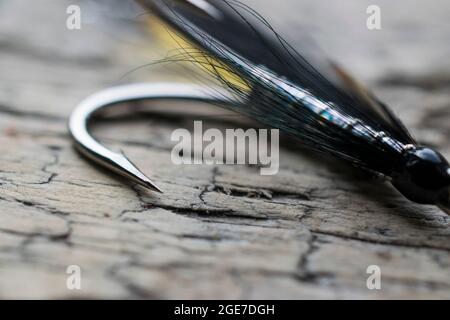Pesca di salmone lucido volare con flash giallo su una superficie di legno Foto Stock