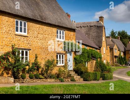 Regno Unito, Inghilterra, Oxfordshire, Wroxton, Main Street, Graziosi cottage Cotswold con tetto in paglia intorno al villaggio verde Foto Stock