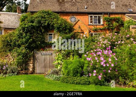 Regno Unito, Inghilterra, Oxfordshire, Balscote, Manor Farm Lane, Sun-dial Cottage con giardino floreale Foto Stock