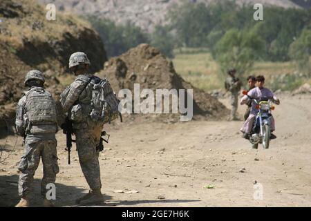 Truppe di combattimento degli Stati Uniti in Afghanistan - due soldati, assegnati a 1-221 Cavalleria Squadron, Nevada National Guard, guardano due ragazzi afghani su una bicicletta mentre passano un checkpoint militare fuori combattimento Outpost Najil nella provincia di Laghman Afghanistan 29 settembre 2009. I 1-221 hanno trascorso nove mesi in Afghanistan, attaccati alla Task Force Mountain Warrior durante la serge del 2009. (STATI UNITI Army Photo by SPC. Walter H. Lowell) Foto Stock