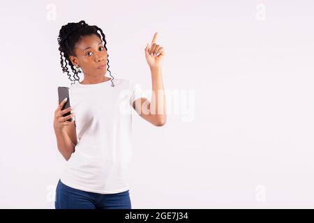 Donna afro-americana che punta verso l'alto e guarda in modo sterno alla telecamera Foto Stock