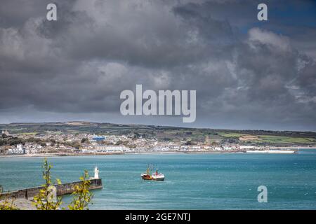 La barca da pesca si avvicina al porto di Newlyn con le nuvole pesanti sullo sfondo, Cornovaglia, Inghilterra. Foto Stock