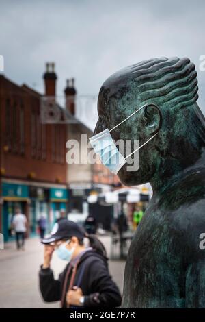 "The Sock Man" dell'artista scozzese Shona Kinloch rappresenta l'industria calzetteria di Loughborough e qui si vede con una maschera facciale e una pedina similmente mascherata Foto Stock