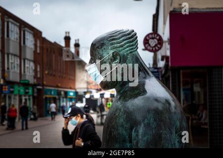 "The Sock Man" dell'artista scozzese Shona Kinloch rappresenta l'industria calzetteria di Loughborough e qui si vede con una maschera facciale e una pedina similmente mascherata Foto Stock