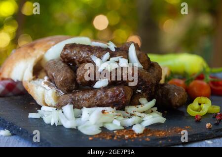 Kebab alla griglia, carne tritata alla griglia in stile turco con cipolla. Cibo tradizionale balcanico - cevapi o cevapcici. Foto Stock