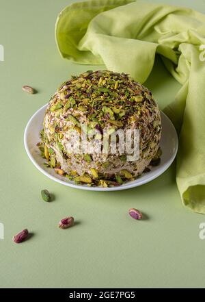 Halva di sesamo con pistacchi, poche noci intere e tovagliolo di lino verde su carta verde. Vista ad angolo alto. Dolci tradizionali mediorientali. Ebreo Foto Stock