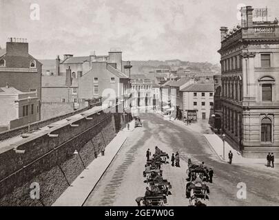 Una vista del tardo 19 ° secolo di Shipquay Place a Derry City, aka Londonderry City, la seconda città più grande dell'Irlanda del Nord. Il nome Derry è un'anglicizzazione del vecchio nome irlandese Daire che significa "boschetto di querce". L'antica città fortificata si trova sulla riva occidentale del fiume Foyle, e la fotografia mostra (a sinistra) le mura della città costruite nel 1613–1619 dall'onorevole The Irish Society come difese per i coloni dell'inizio del XVII secolo provenienti dall'Inghilterra e dalla Scozia. Foto Stock