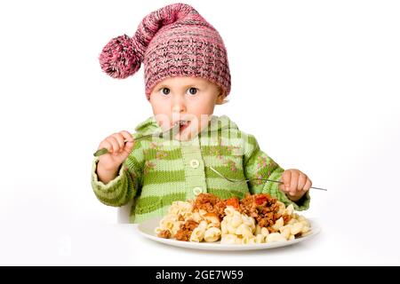 Bel bambino che mangia la pasta, isolato su bianco Foto Stock