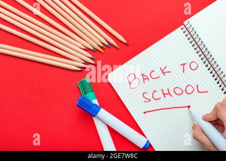 Ritorno a scuola. Il bambino scrive di nuovo a scuola in un notebook in un pennarello rosso. Il concetto di inizio dell'anno scolastico. Banner per il sito su un Foto Stock