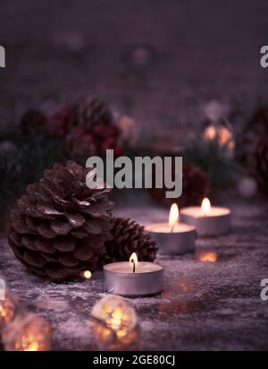Candele accese, coni di cedro e rami di abete per Natale in un'atmosfera casalinga. Stile di vita Foto Stock