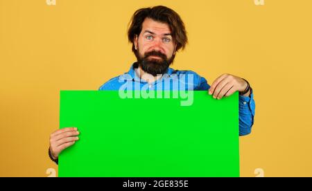 Uomo bearded con cartello vuoto. Sorridente maschio con banner pubblicitario. Spazio per il testo. black friday. Vendita e sconto. Foto Stock