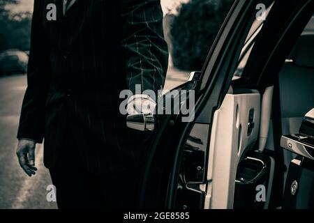 Autista che apre la porta del passeggero dell'auto di lusso Foto Stock