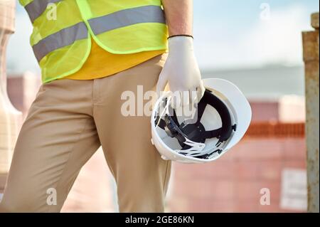 Builder in un gilet riflettente che porta il suo hardhat Foto Stock