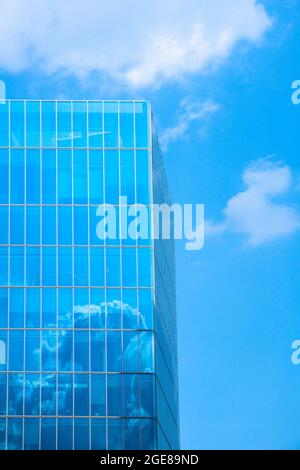 Moderno edificio in vetro per uffici d'affari con cielo blu e nuvole in riflesso delle finestre Foto Stock
