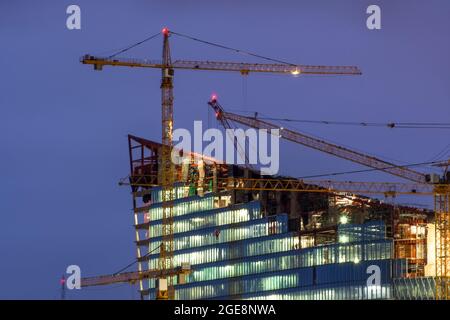 Gru sulla parte superiore dell'edificio in costruzione di notte Foto Stock