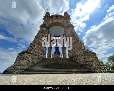 Monumento dell'Imperatore Guglielmo sotto la luce del sole e un cielo blu nuvoloso a porta Westfalica, Germania Foto Stock