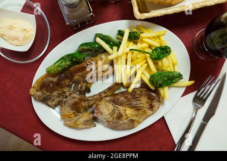 Gustose costolette di agnello al forno servite con patate fritte e pepe verde Foto Stock