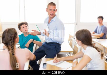 Insegnante positivo che aiuta gli studenti adolescenti durante la lezione Foto Stock