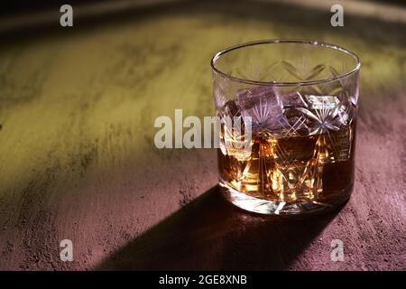 Primo piano di un bicchiere di whiskey con ombra su una superficie ruvida Foto Stock
