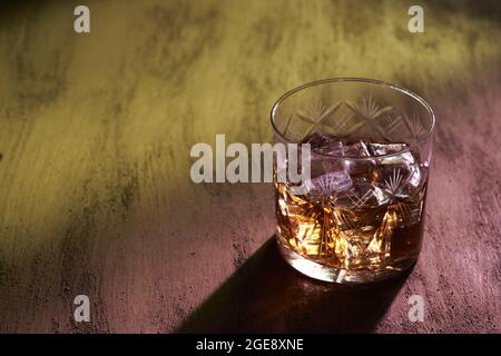 Primo piano di un bicchiere di whiskey con ombra su una superficie ruvida Foto Stock