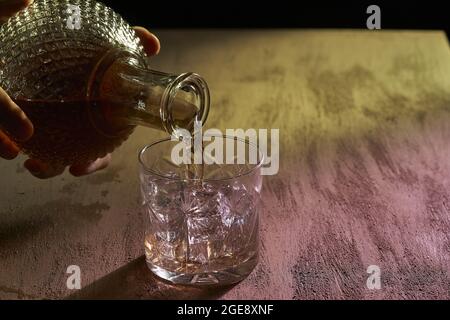 Uomo che versa un whiskey su un bicchiere con ghiaccio Foto Stock