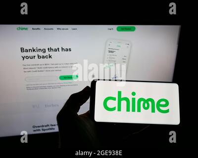 Persona che tiene uno smartphone con il logo della società statunitense FinTech Chime Financial Inc. Sullo schermo di fronte al sito Web. Mettere a fuoco sul display del telefono. Foto Stock