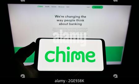 Persona che tiene il telefono cellulare con il logo della società FinTech statunitense Chime Financial Inc. Sullo schermo di fronte alla pagina web aziendale. Mettere a fuoco sul display del telefono. Foto Stock