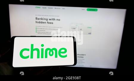 Persona che tiene il cellulare con il logo della società americana fintech Chime Financial Inc. Sullo schermo di fronte al sito web aziendale. Mettere a fuoco sul display del telefono. Foto Stock