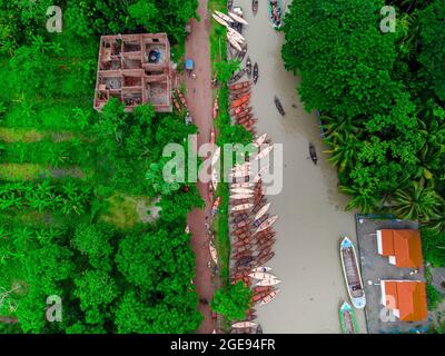 Barishal, Barishal, Bangladesh. 18 agosto 2021. I produttori di barche al settimanale 'Noukar Haat' (mercato delle barche) in Kuriana sotto la Swarupkathi upazila del distretto di Pirojpur nella divisione di Barishal in Bangladesh stanno facendo il commercio del rischio durante questa stagione del monsone. Il mercato lungo due chilometri è noto per il commercio di diverse varietà di imbarcazioni durante la stagione monsonica. Il mercato è attivo ogni venerdì da maggio a novembre. 'Panis' o 'pinis', 'Dingi' e 'NAAK Golui' sono i tipi di barche disponibili per la vendita, costruiti da artigiani locali da Muktahar, Chami, Boldia, Inderhaat, B. Foto Stock