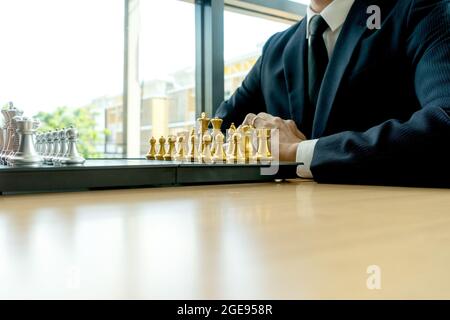 Un uomo d'affari che indossa un vestito si prepara a giocare a scacchi di fronte al concetto di strategia scacchi da tavolo con più spazio di copia Foto Stock