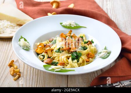 Deliziosa pasta italiana con chanterelle fresche, spinaci giovani, salsa alla crema e parmigiano Foto Stock